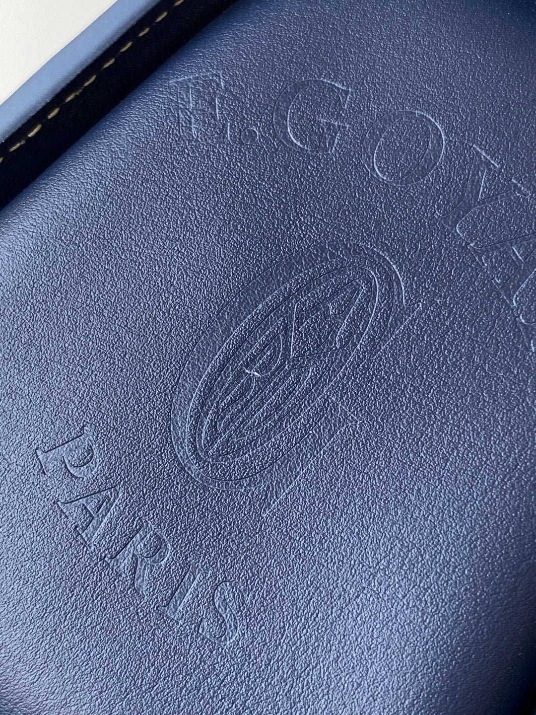 Goyard bag close-up of embossed blue leather with signature logo pattern texture.