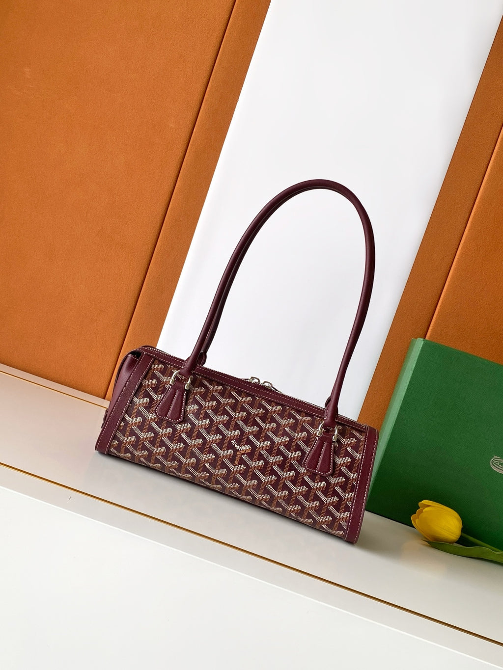 Burgundy geometric logo handbag with curved top handle and front strap
