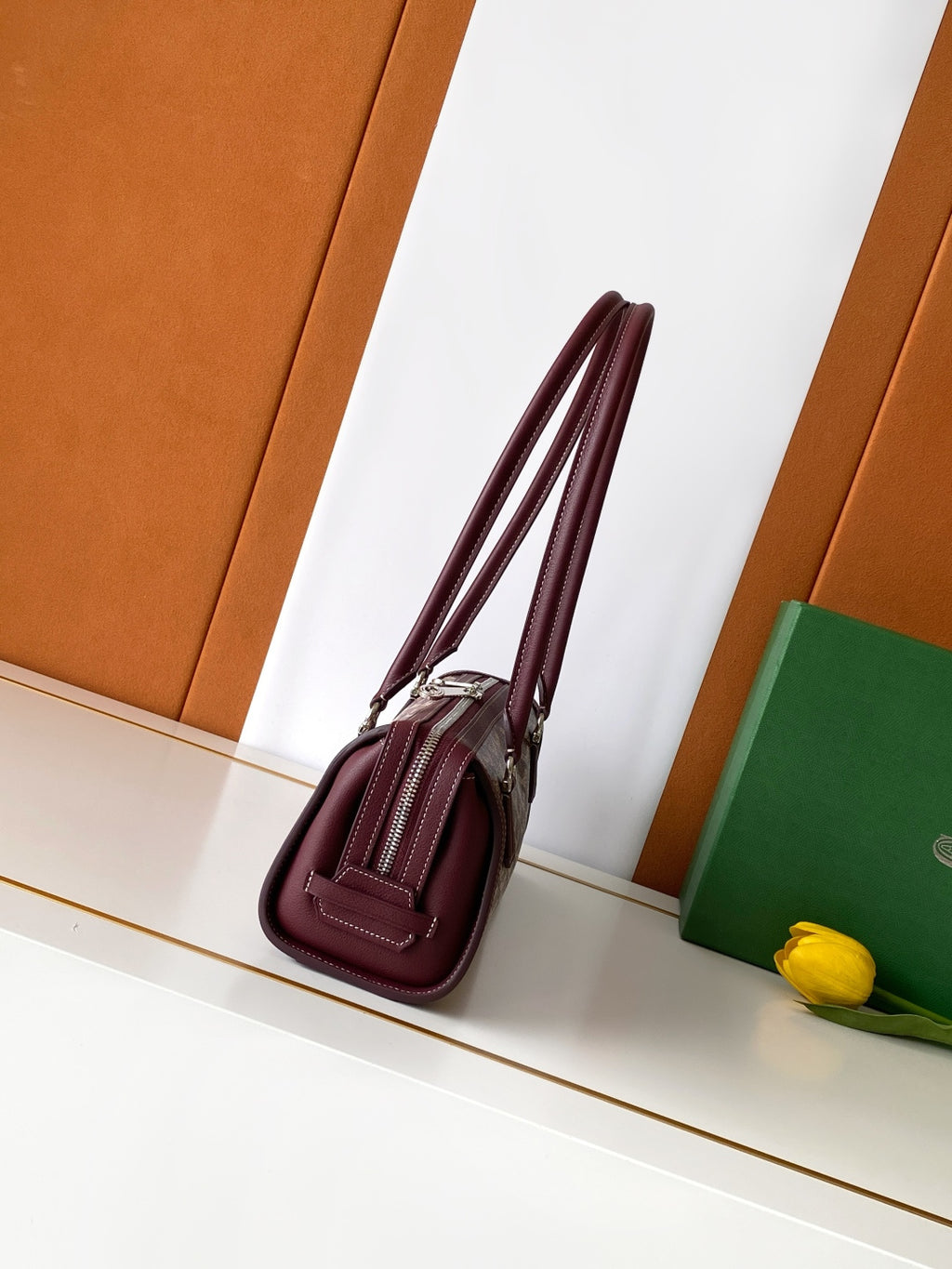 Burgundy patterned handbag with long strap and zip closure, side view