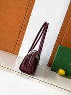 Burgundy patterned handbag with long strap and zip closure, side view