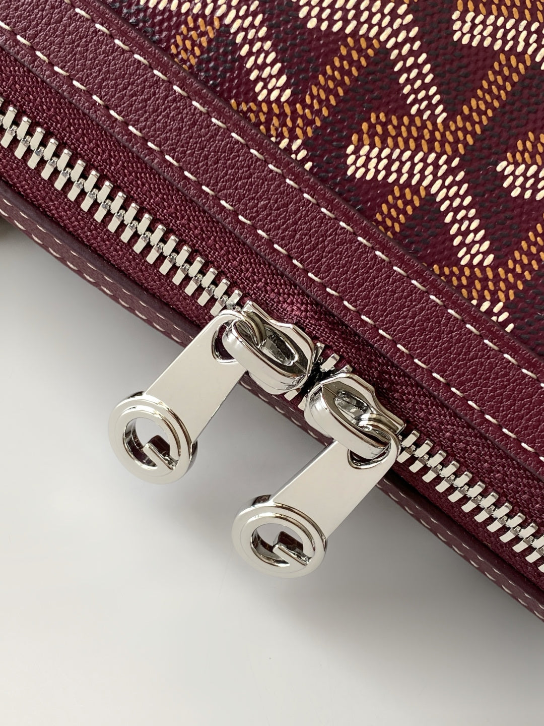 Burgundy zip pocket detail with silver hardware and stitched edge