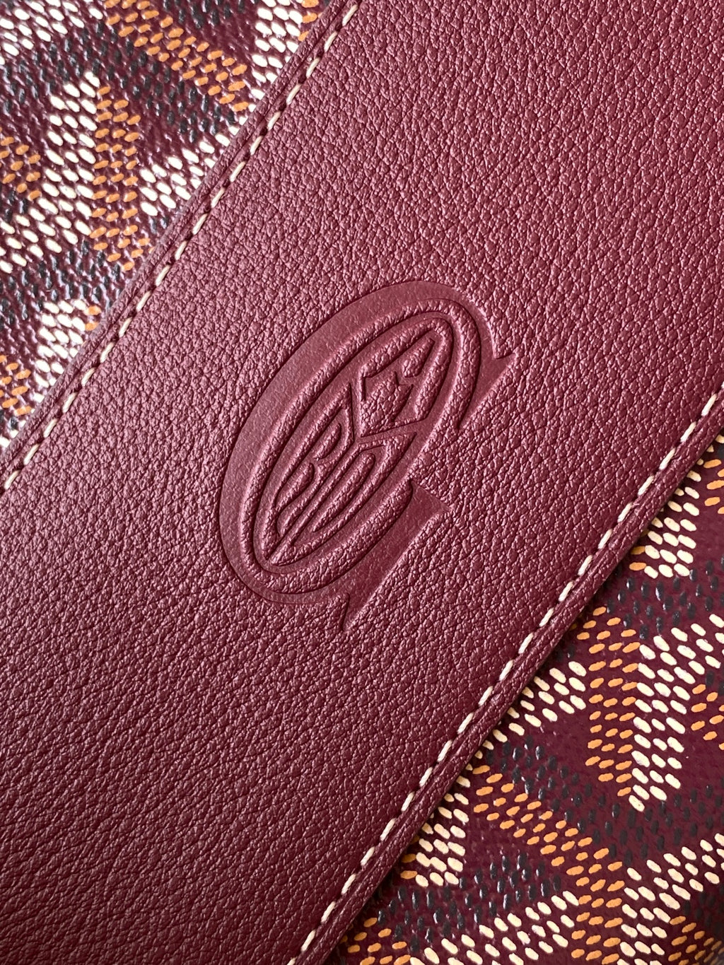Burgundy leather panel with embossed oval logo and contrast stitching