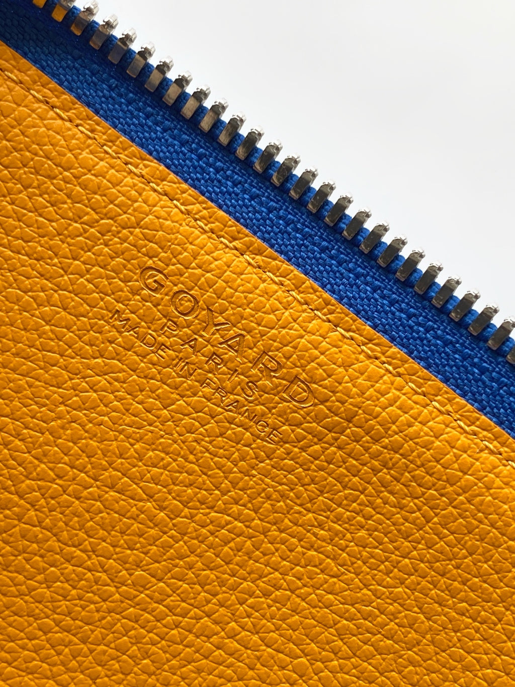 Mustard-yellow leather lining with embossed Goyard logo and blue zipper trim