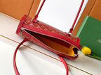 Red patterned zip-top handbag with crossbody strap and top handle