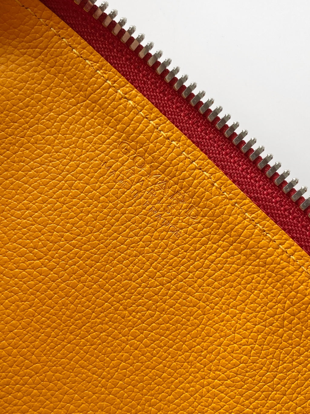 Yellow textured leather lining with red zipper trim and metal teeth