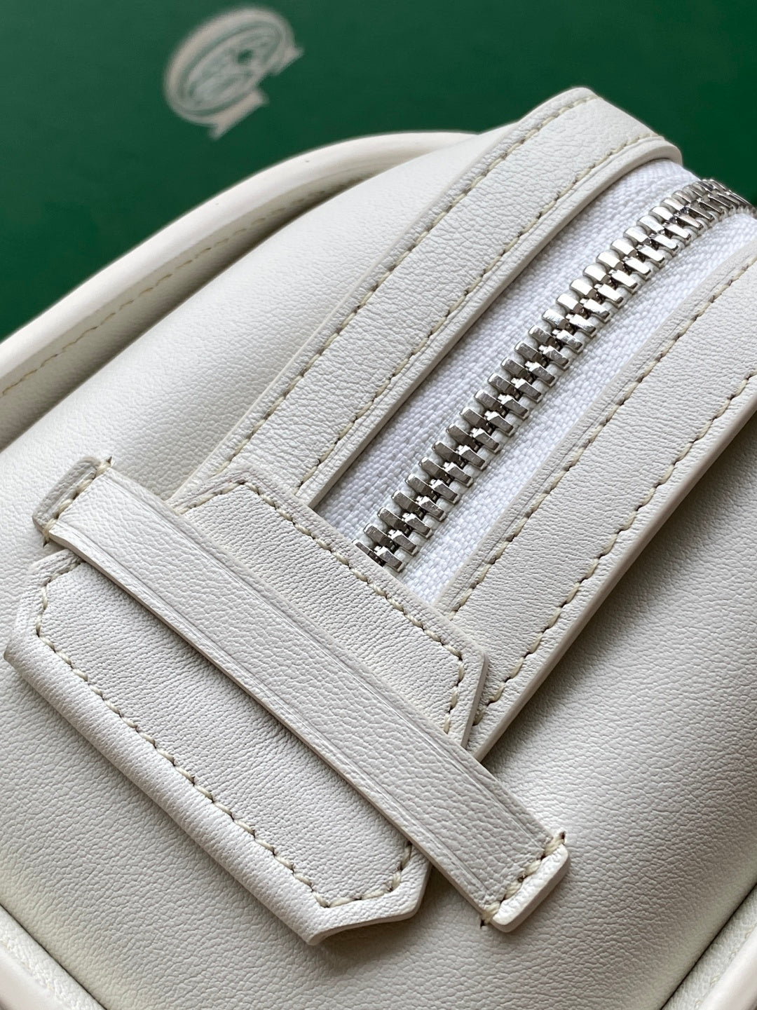 Goyard white leather bag close-up with zipper teeth and stitched seams