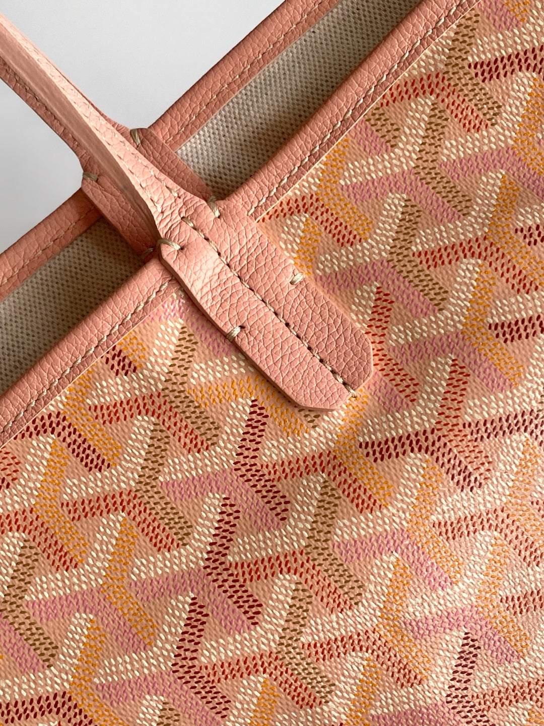 Pink patterned fabric with leather handle attachment and visible stitching