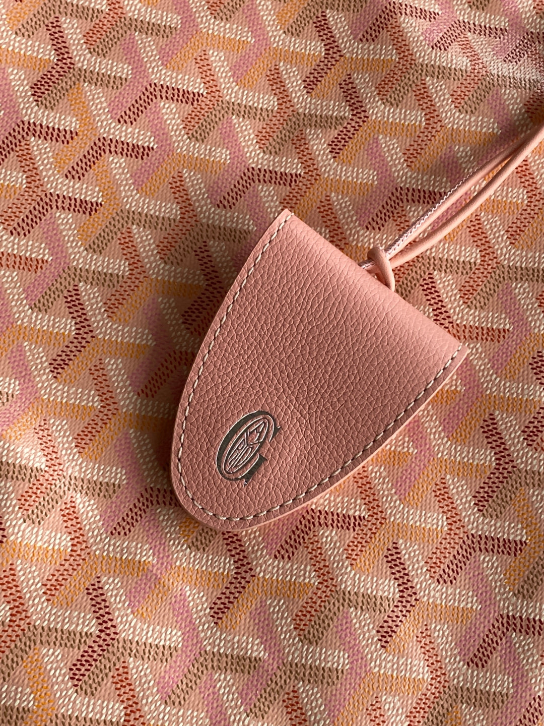 Pink patterned canvas with a tan leather tab and round logo emblem