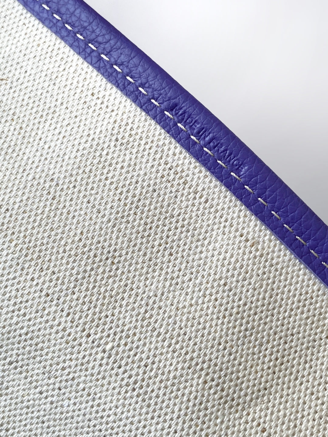Purple leather trim with contrast stitching on textured canvas