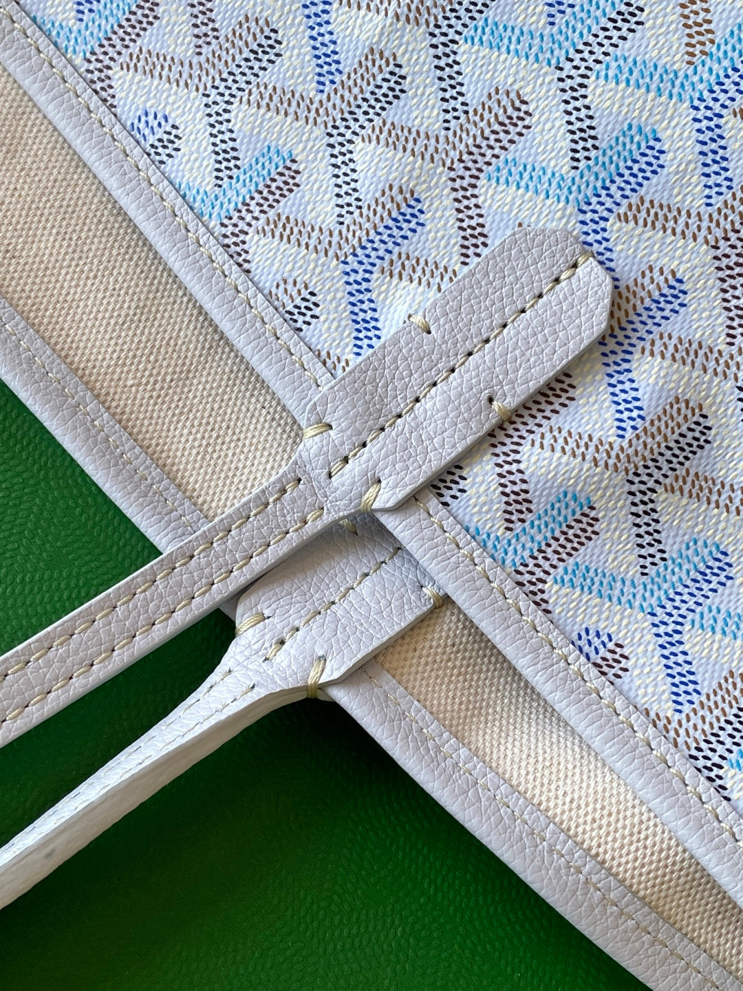 White leather strap with stitching on light blue patterned tote bag