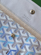 Round metal snap button and stitched leather panel on light blue patterned tote