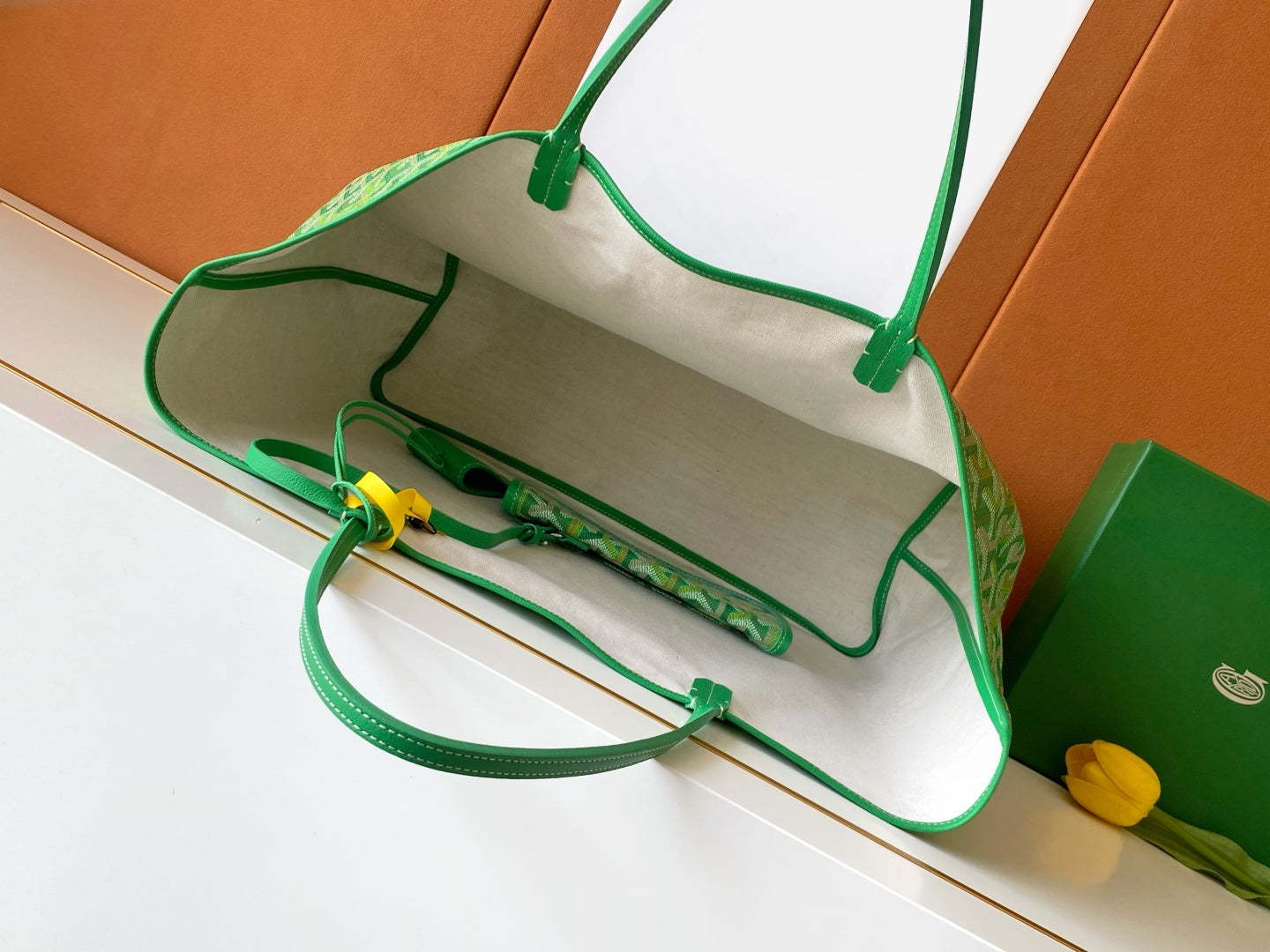 Goyard tote bag with top handles and green strap shown inside