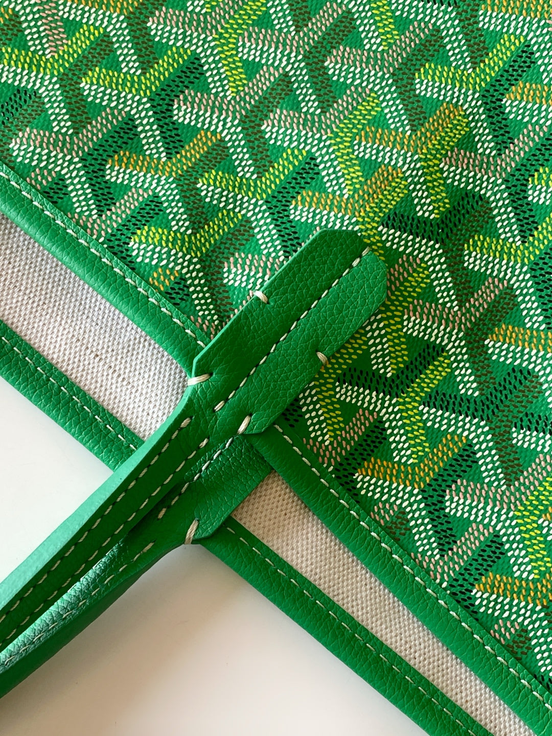 Goyard tote bag corner with green fabric lining and stitched leather trim