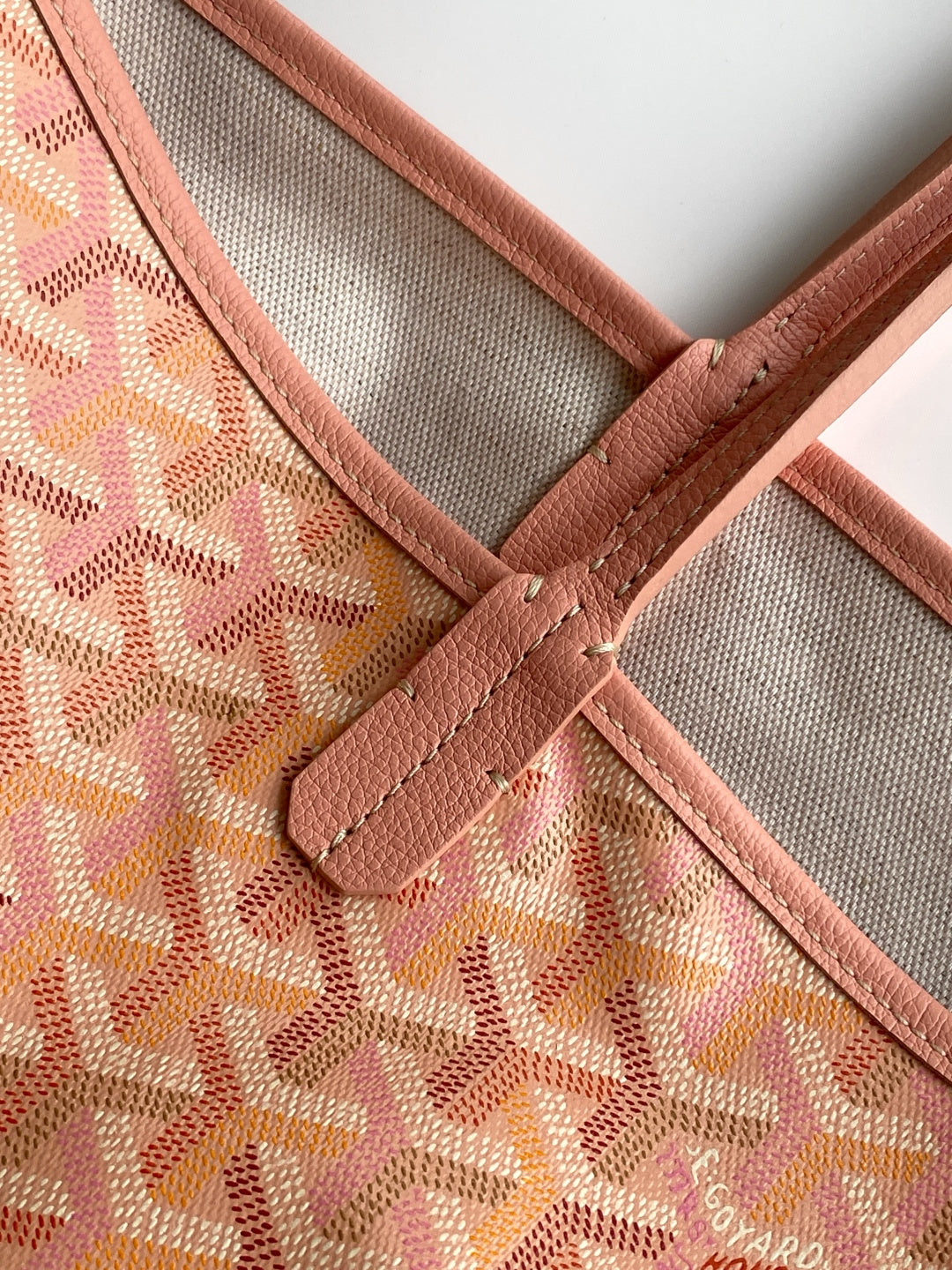 Tote bag interior panel with gray lining, pink trim, and stitched leather seam