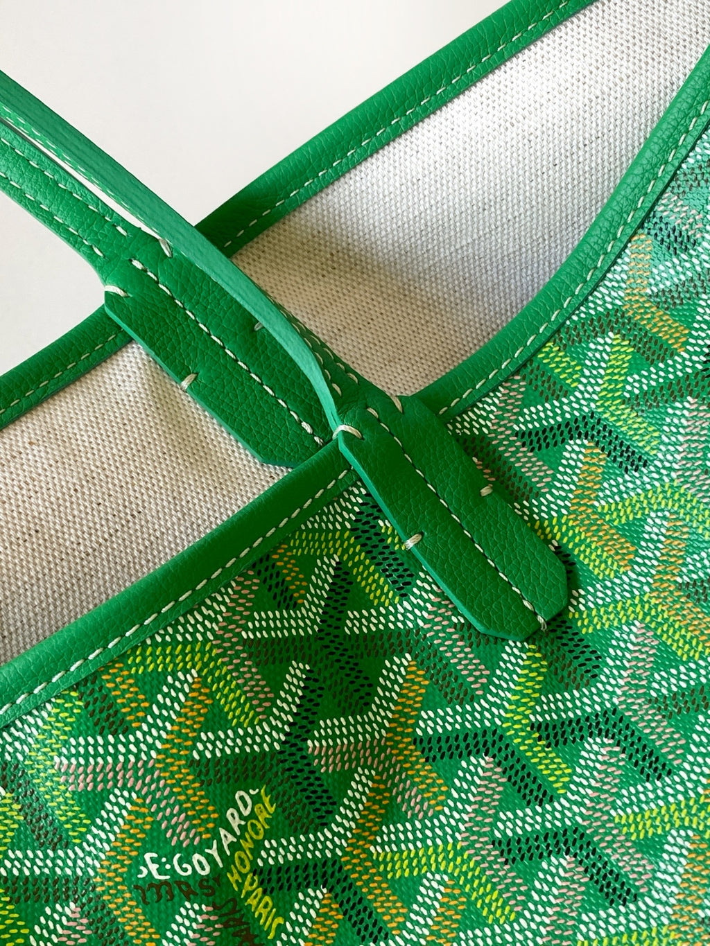 Green patterned tote bag close-up with stitched green trim and logo print