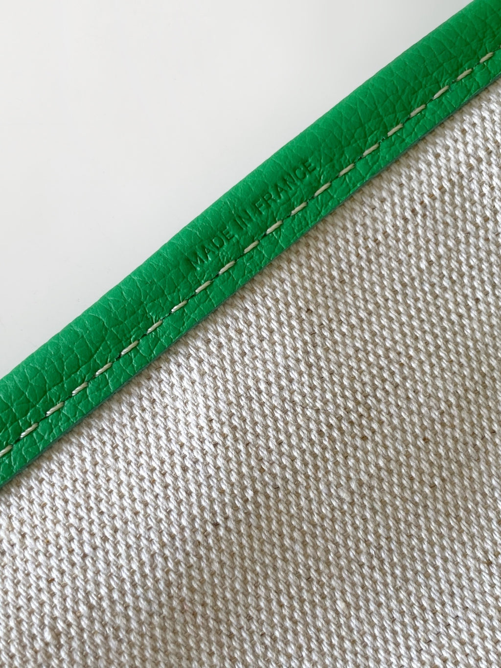 Green leather-trim tote bag edge with visible stitching and textured exterior