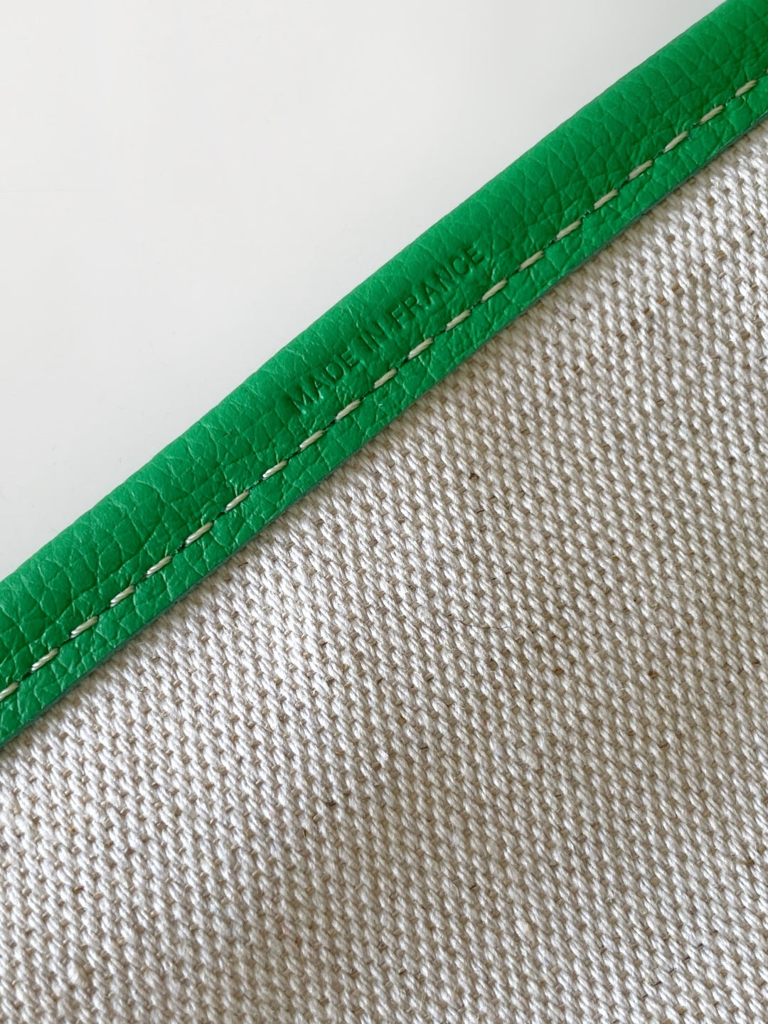 Green leather-trim tote bag edge with visible stitching and textured exterior