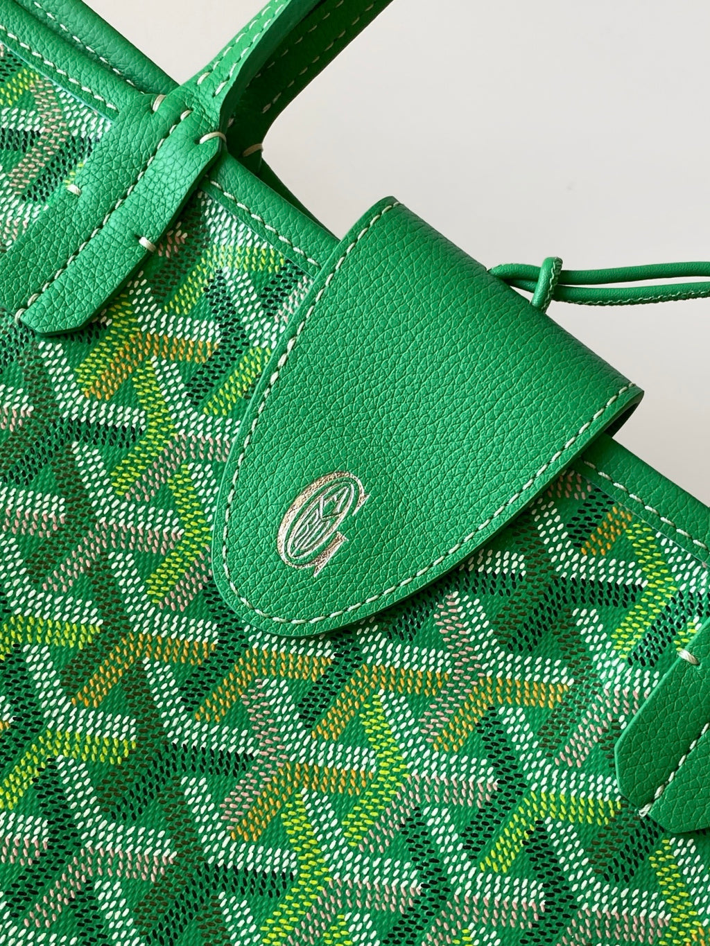Green patterned tote bag close-up of leather tab with snap and stitch detail