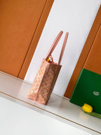 Pink patterned tote bag shown in side view with tall leather handles.