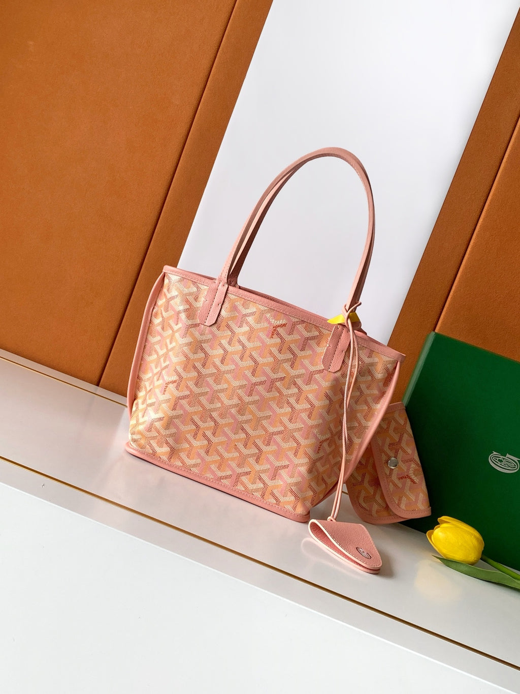 Pink patterned tote bag with two top handles and a small bow detail.