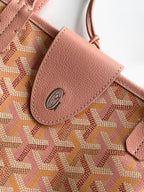 Pink patterned bag with leather tab and circular logo on the front pocket.