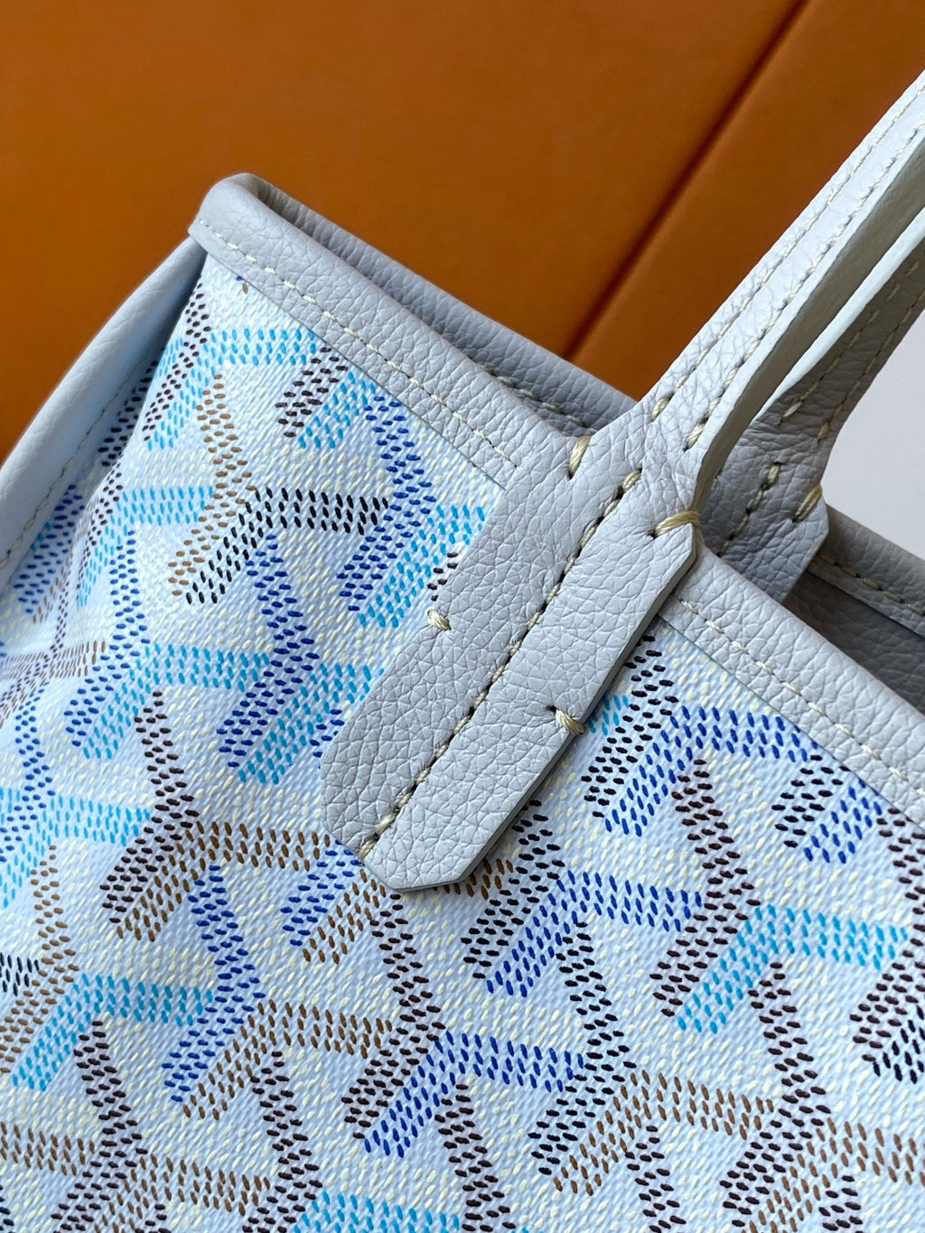 Close-up of light blue patterned tote bag pocket and stitched leather tab