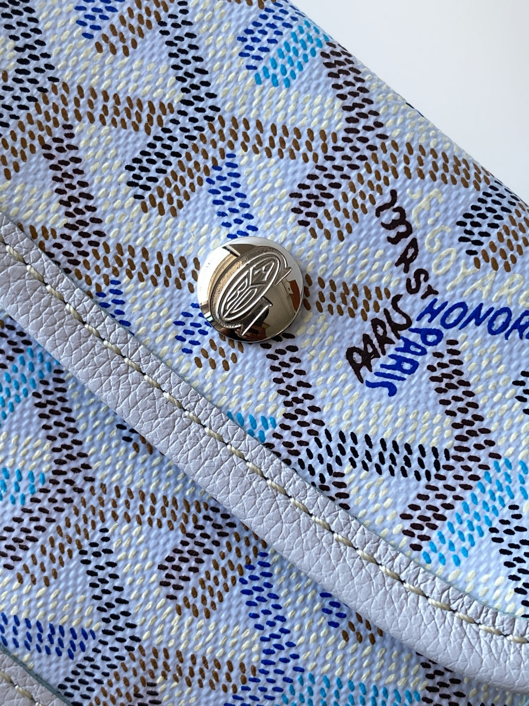 Light blue monogram tote bag top closure with round metal logo button