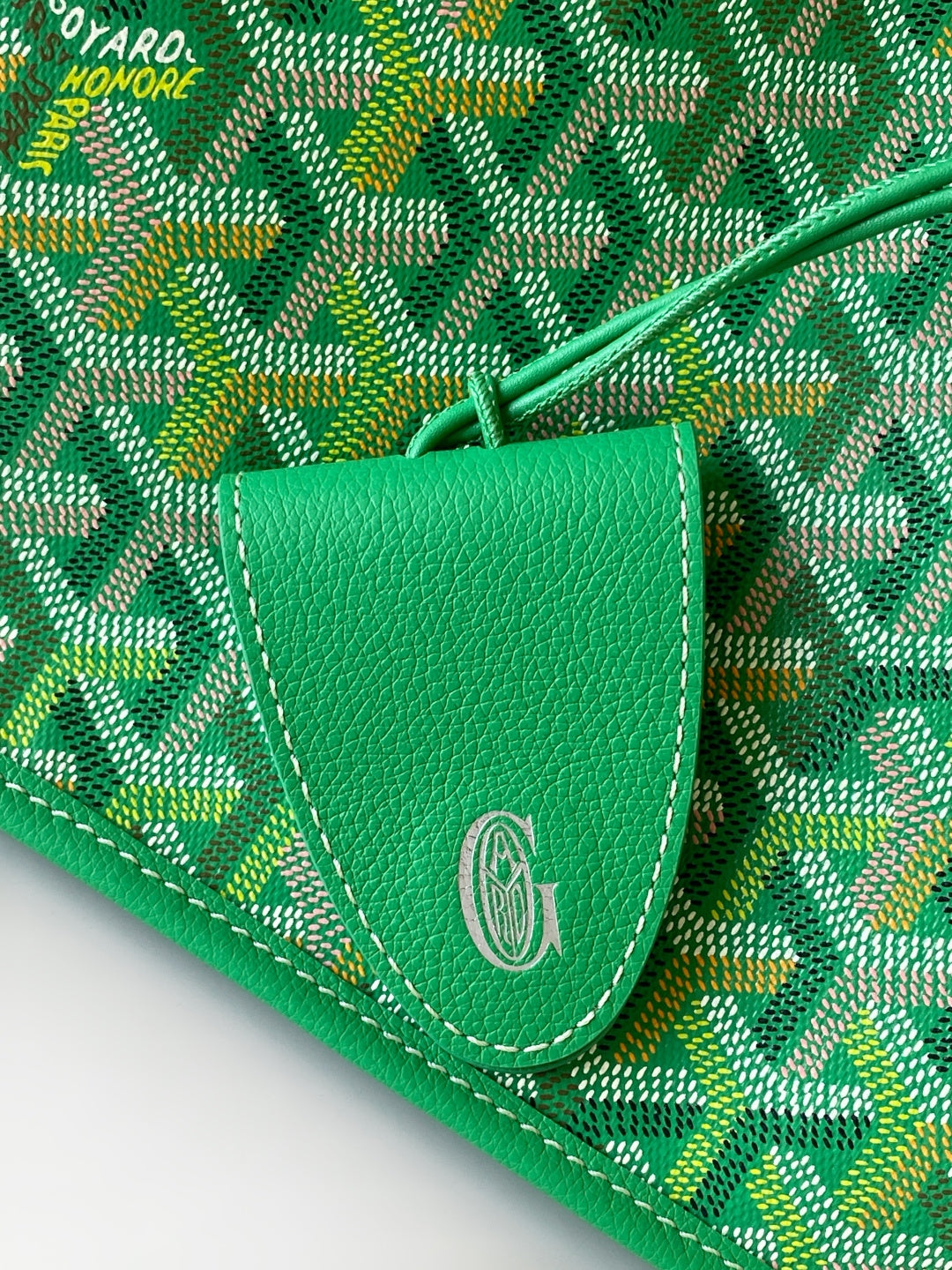 Green patterned tote bag tab with stitched edge and oval emblem