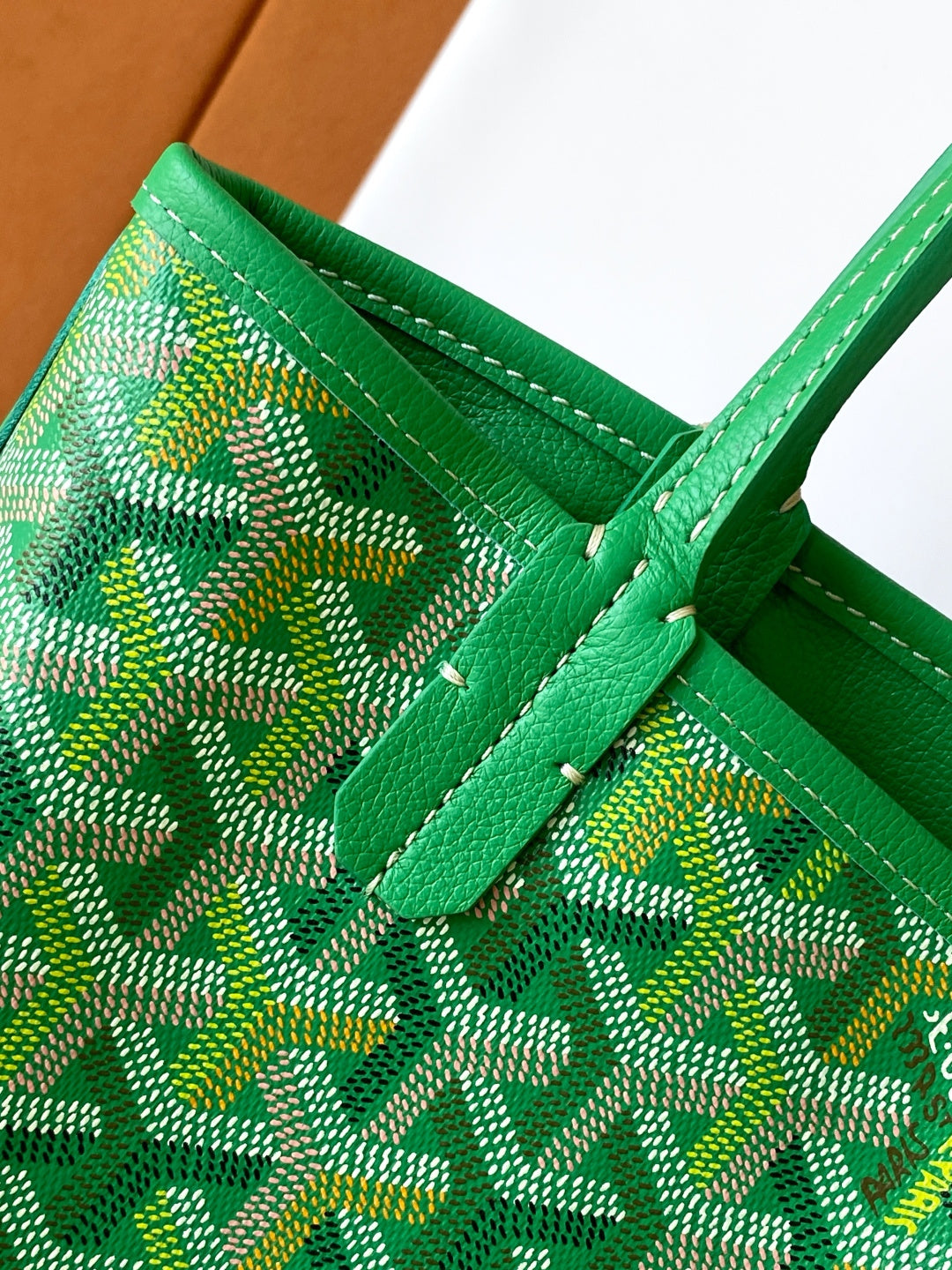 Green patterned tote bag corner with stitched trim and green strap