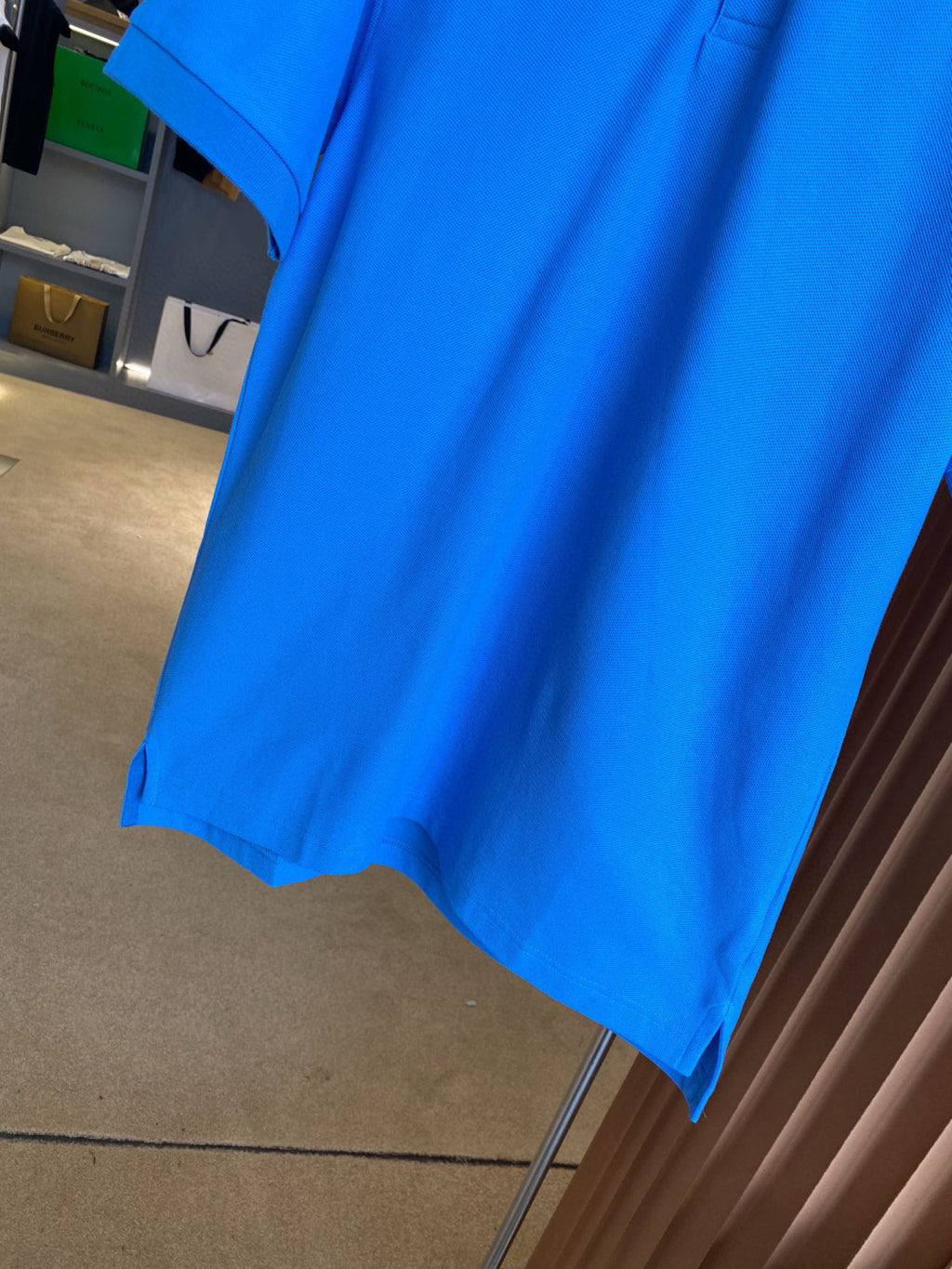 Blue Burberry polo shirt hem on hanger, short sleeves and curved bottom