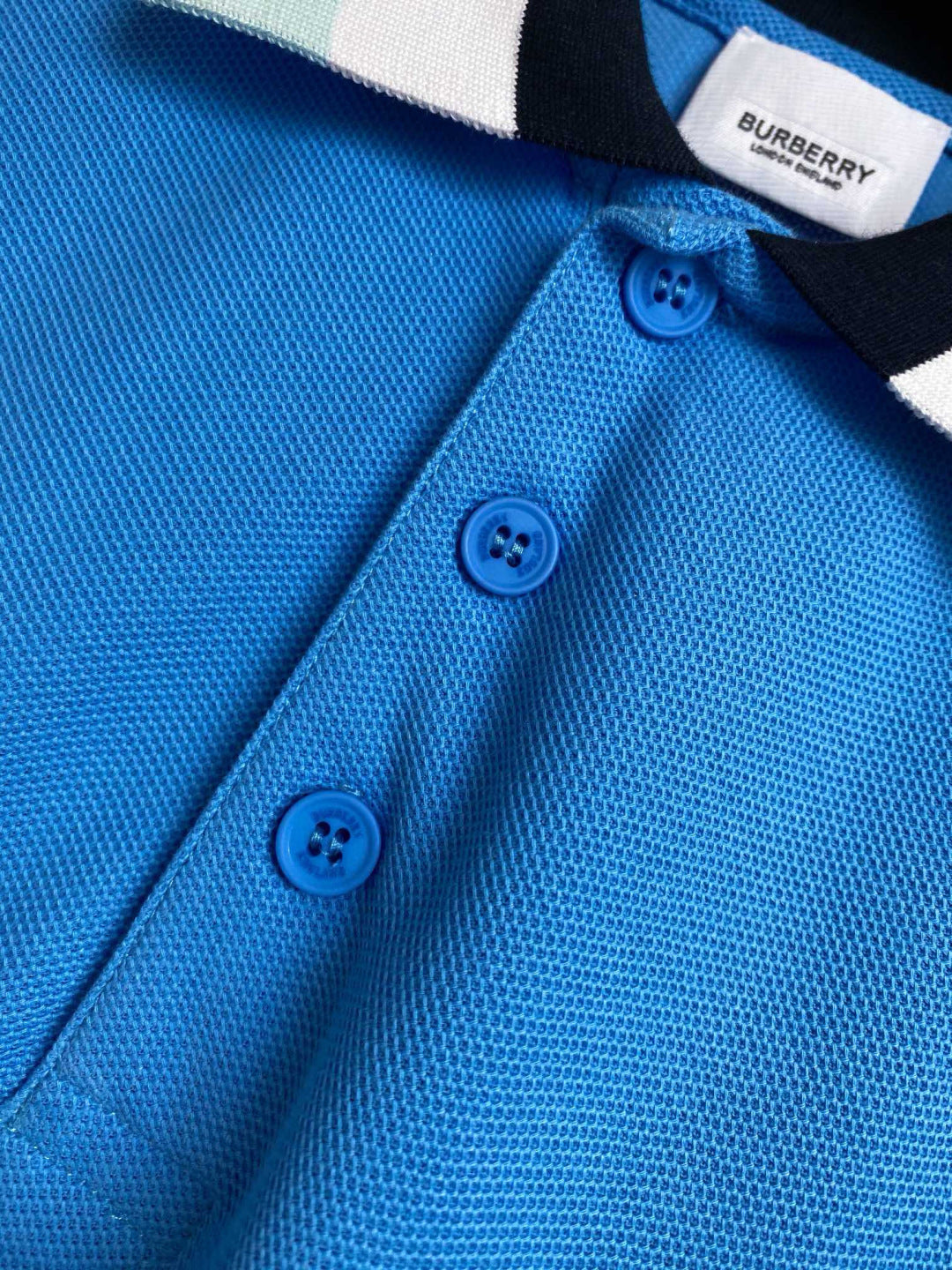 Blue Burberry polo shirt front close-up, three blue buttons on placket