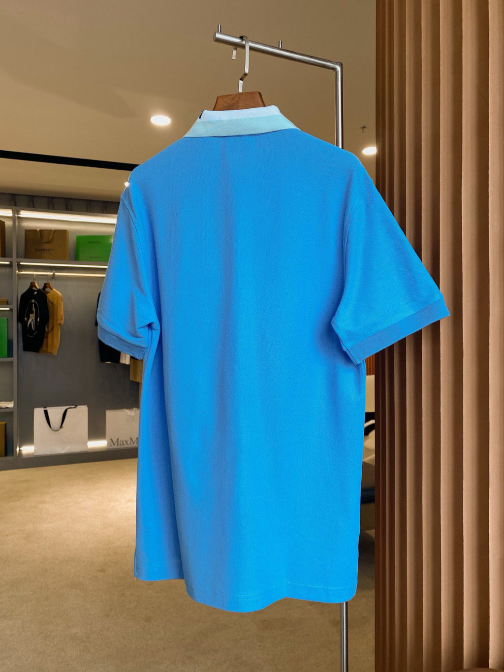 Blue Burberry polo shirt, back view on hanger with short sleeves