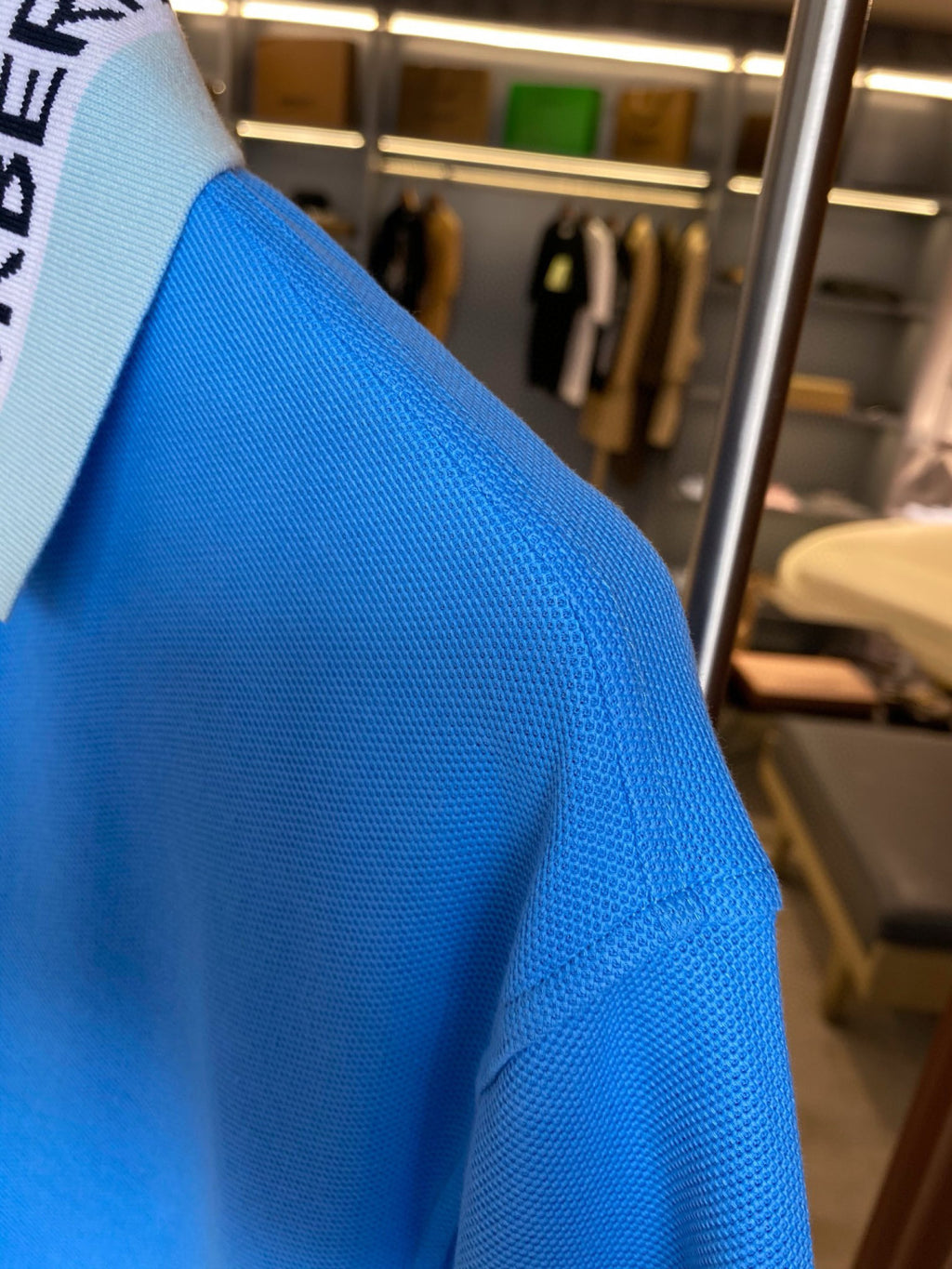 Blue Burberry polo shirt shoulder and side seam detail on hanger