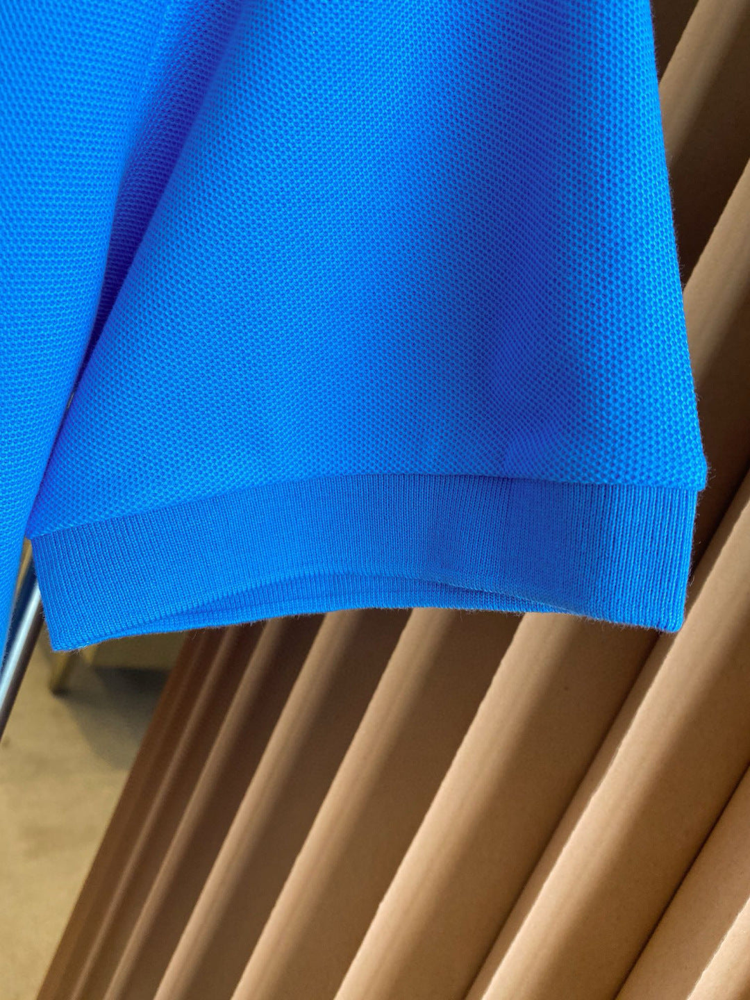Blue Burberry polo shirt sleeve cuff and hem detail on hanger