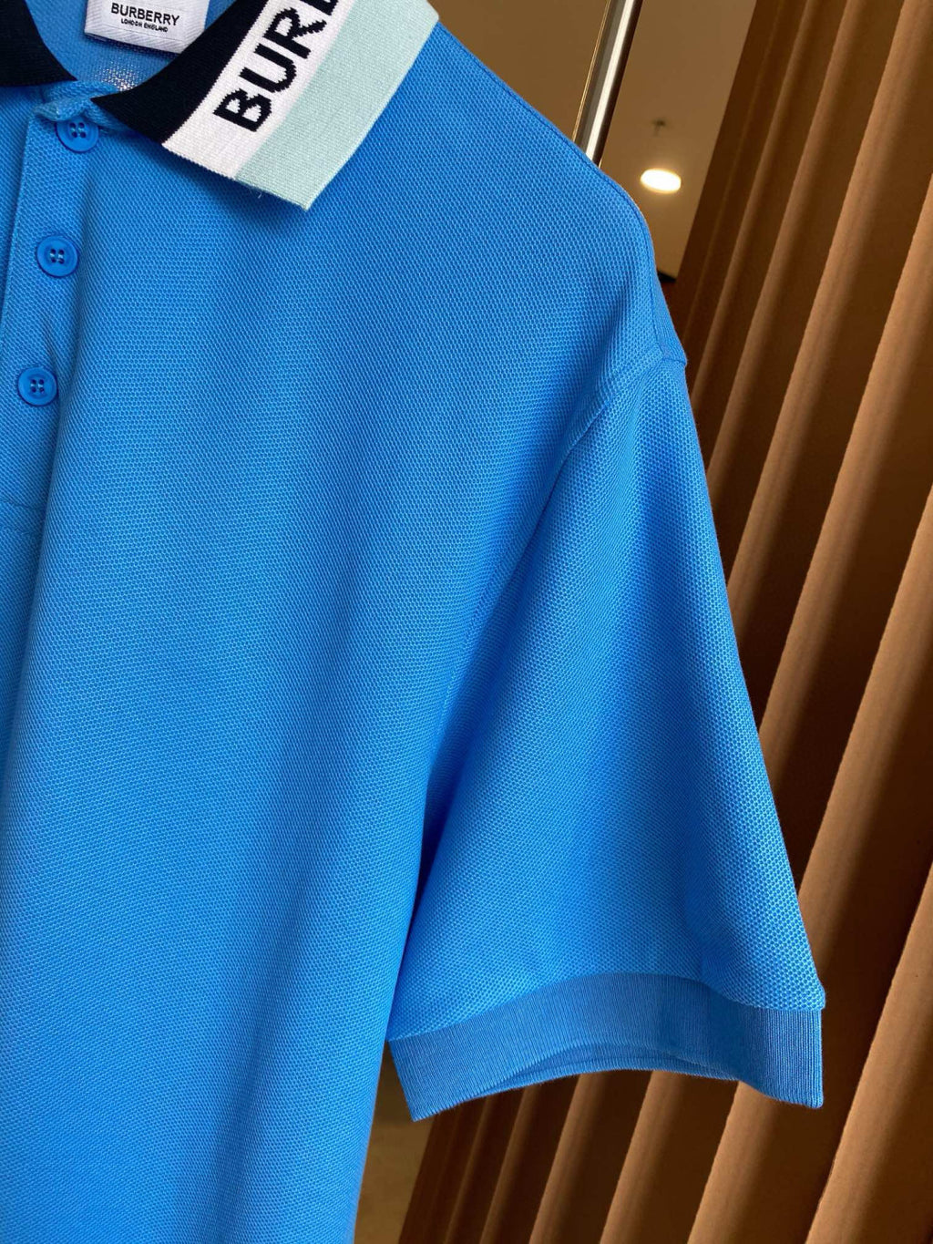 Blue Burberry polo shirt sleeve and collar detail with front button placket