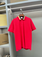 Red polo shirt with button placket and striped collar, on a hanger