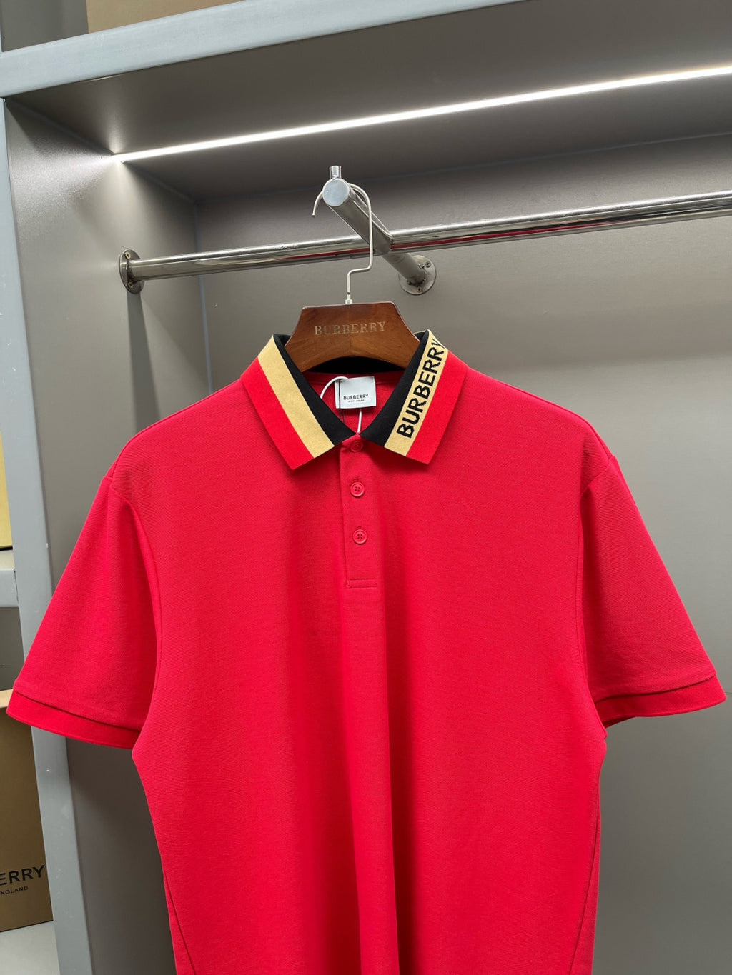 Red polo shirt with collar detail and Burberry logo label on hanger