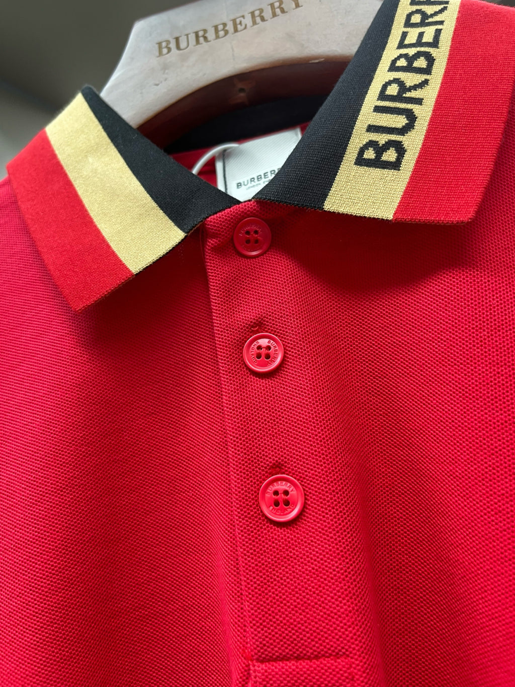 Red polo shirt neckline and buttons with striped Burberry collar