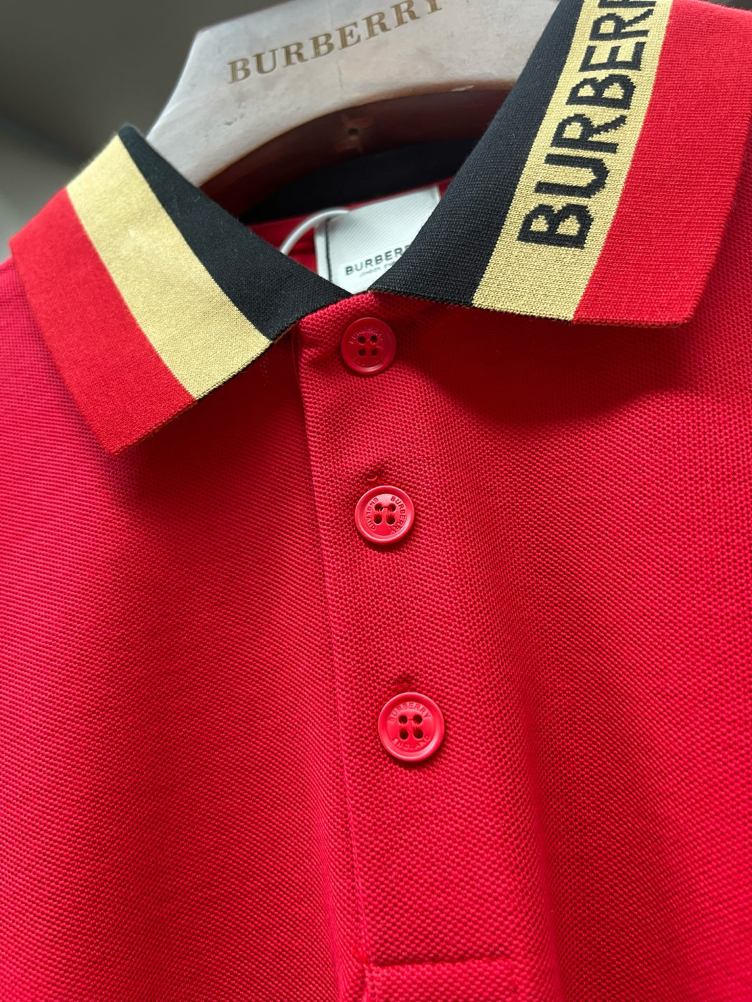 Red polo shirt neckline and buttons with striped Burberry collar