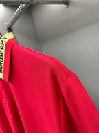 Red polo shirt sleeve and side seam with Burberry collar stripe