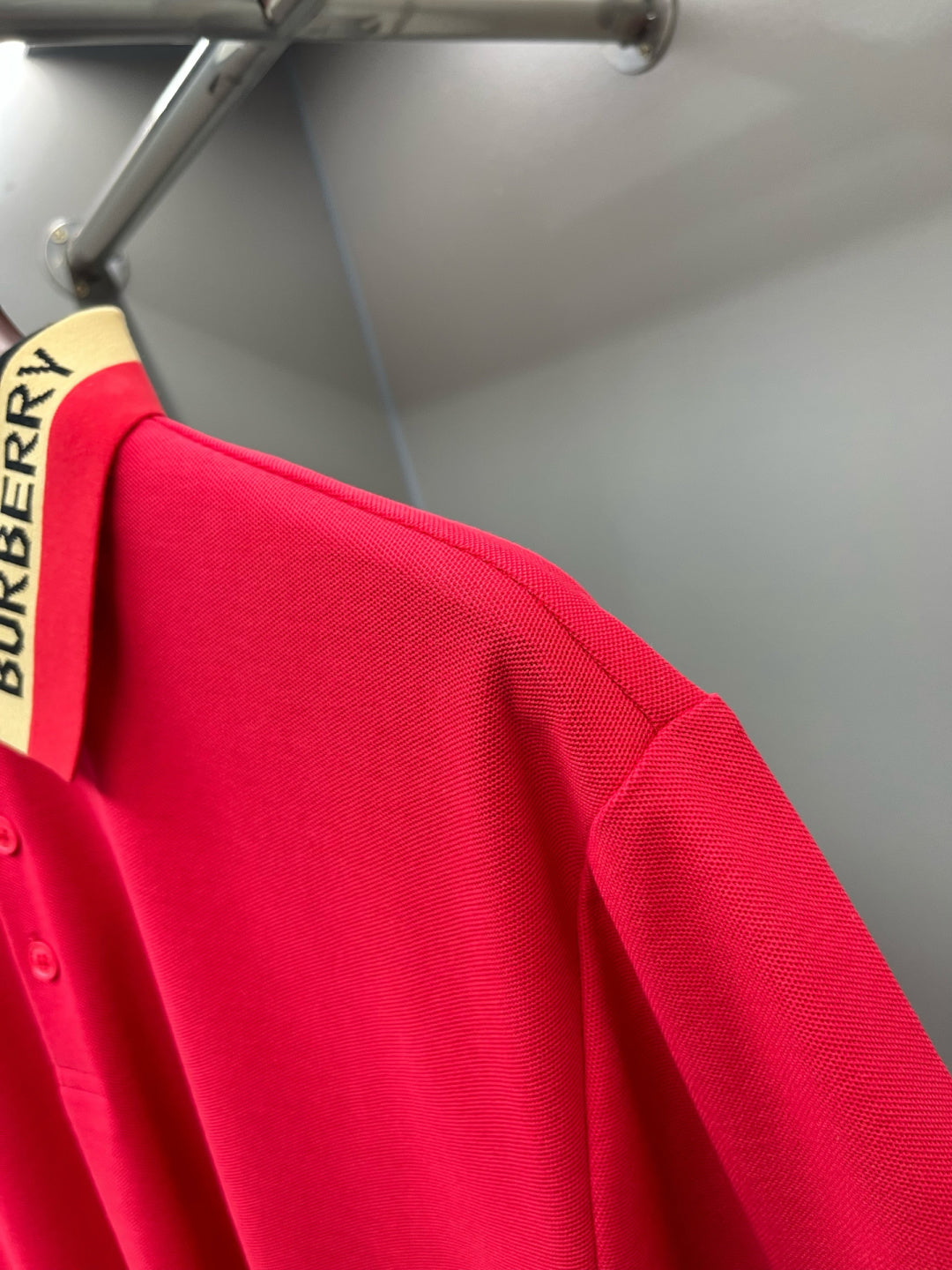 Red polo shirt sleeve and side seam with Burberry collar stripe