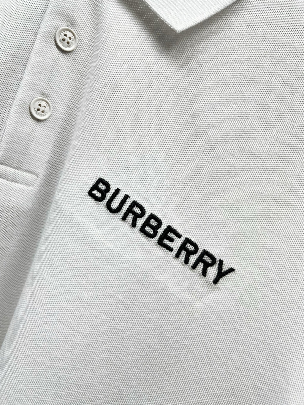 Close-up of Burberry wordmark on white polo shirt fabric