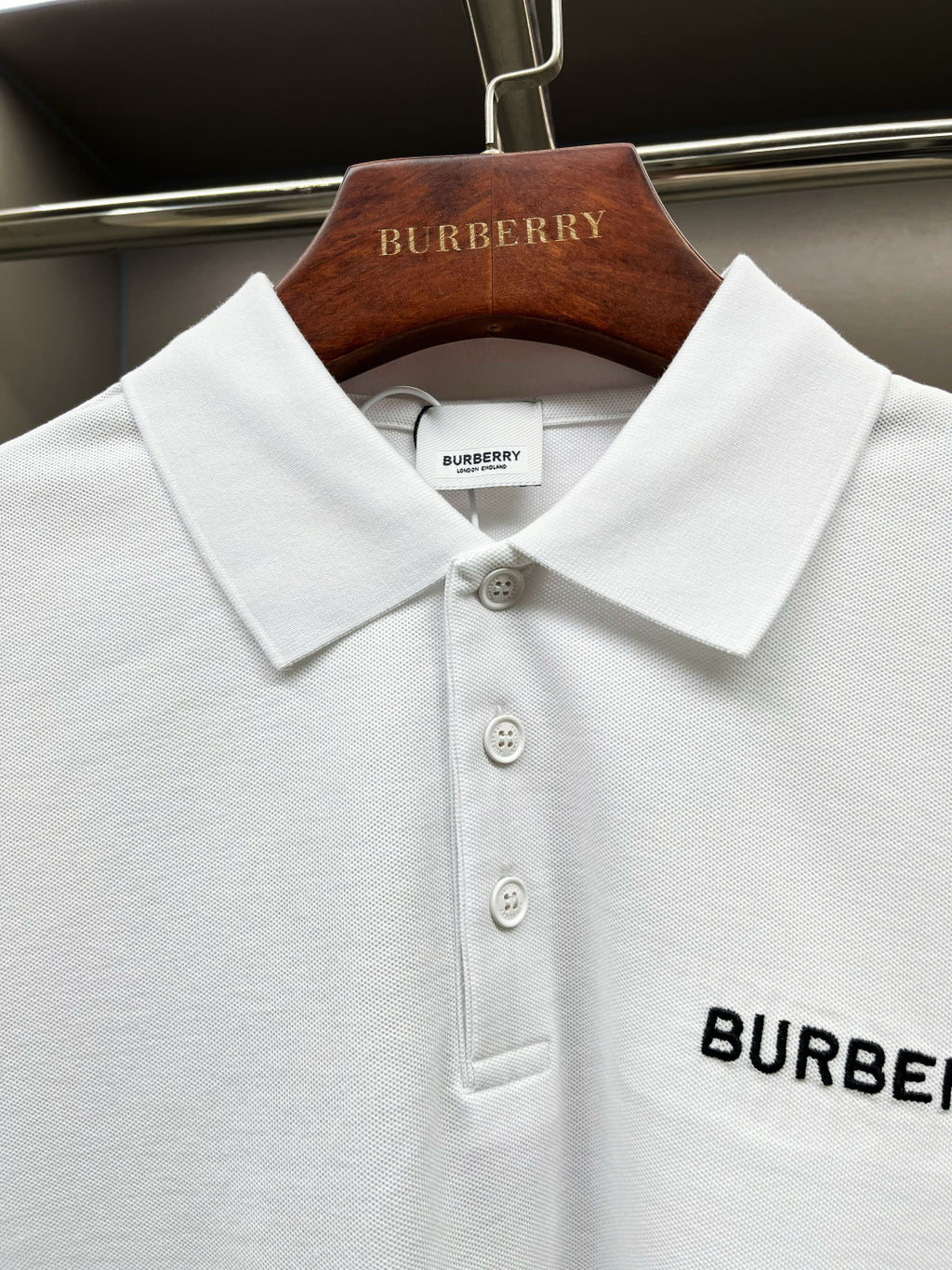Close-up of white Burberry polo collar with three button front and logo patch