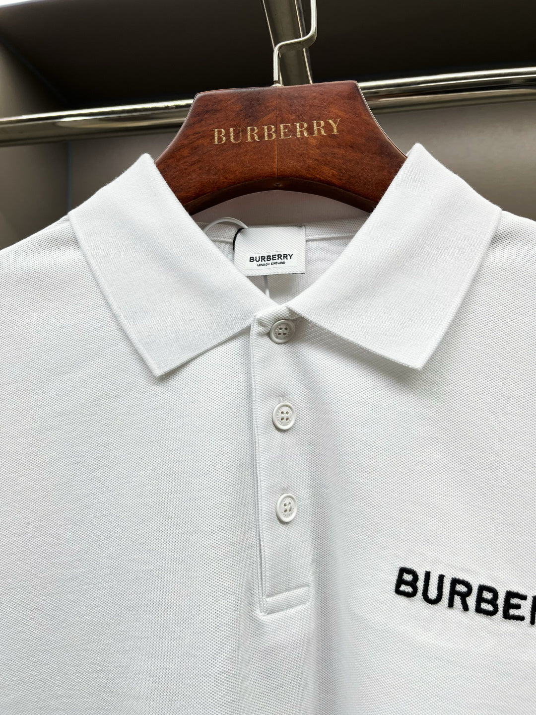 Close-up of white Burberry polo collar with three button front and logo patch