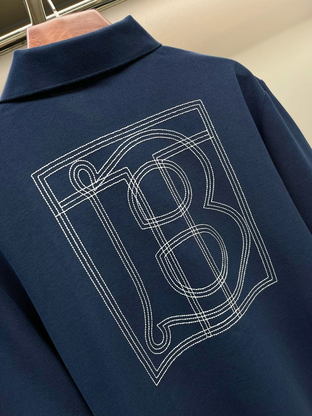 Blue polo shirt back with large TB monogram graphic, embroidered lines