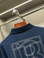 Blue polo shirt back with TB monogram graphic in outlined lines