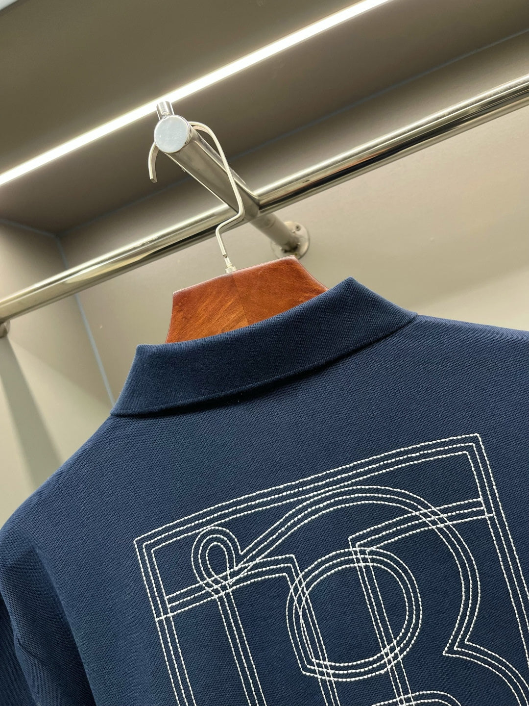 Blue polo shirt back with TB monogram graphic in outlined lines