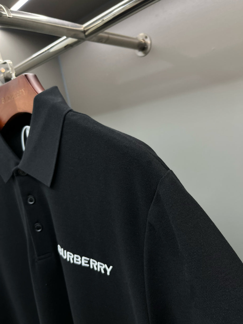 Black short-sleeve polo shirt with Burberry logo print on side.