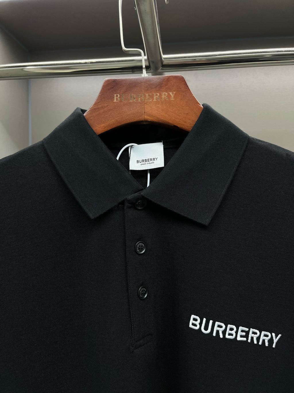 Black short-sleeve polo shirt, collar and Burberry logo print at chest.