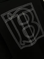 Black polo shirt back graphic print with outlined letters and number-style design.